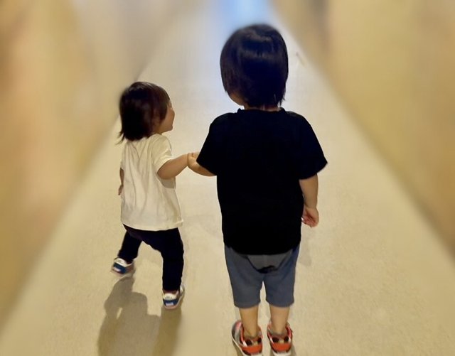 仲良く手を繋いでいる3歳児と1歳児