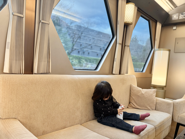 靴を脱いでソファ席でゆったり座っている1歳児の様子